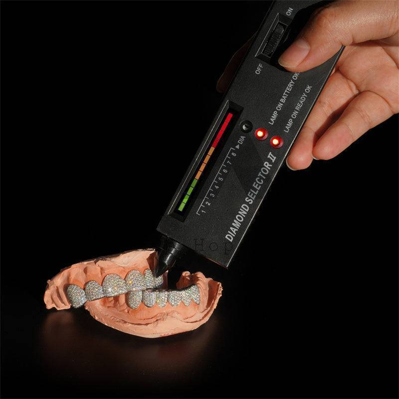 A handheld diamond tester reading in the diamond range on a moissanite grill — CustomHipHop